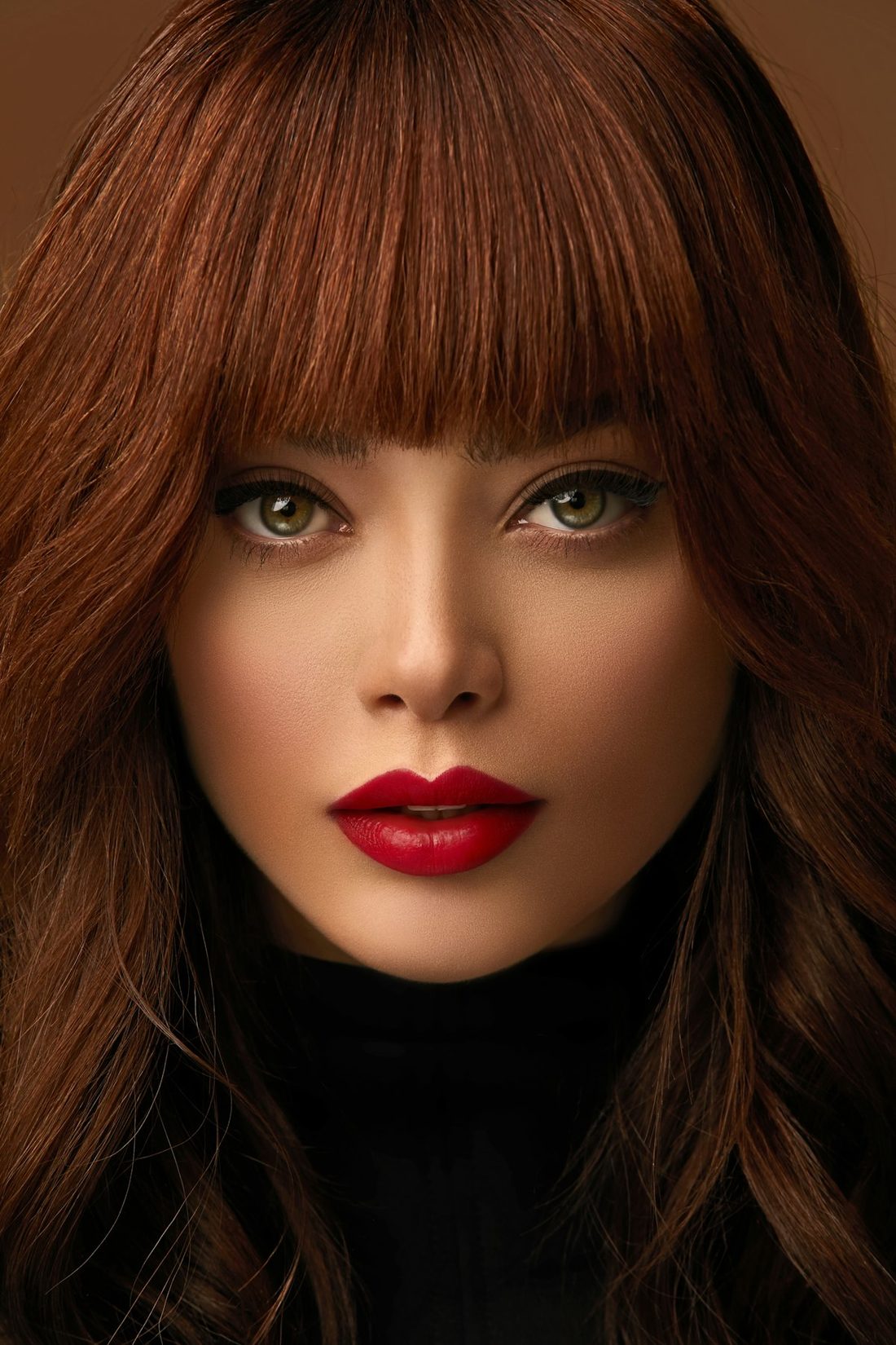 Portrait of a woman with glossy copper balayage hair and a soft fringe