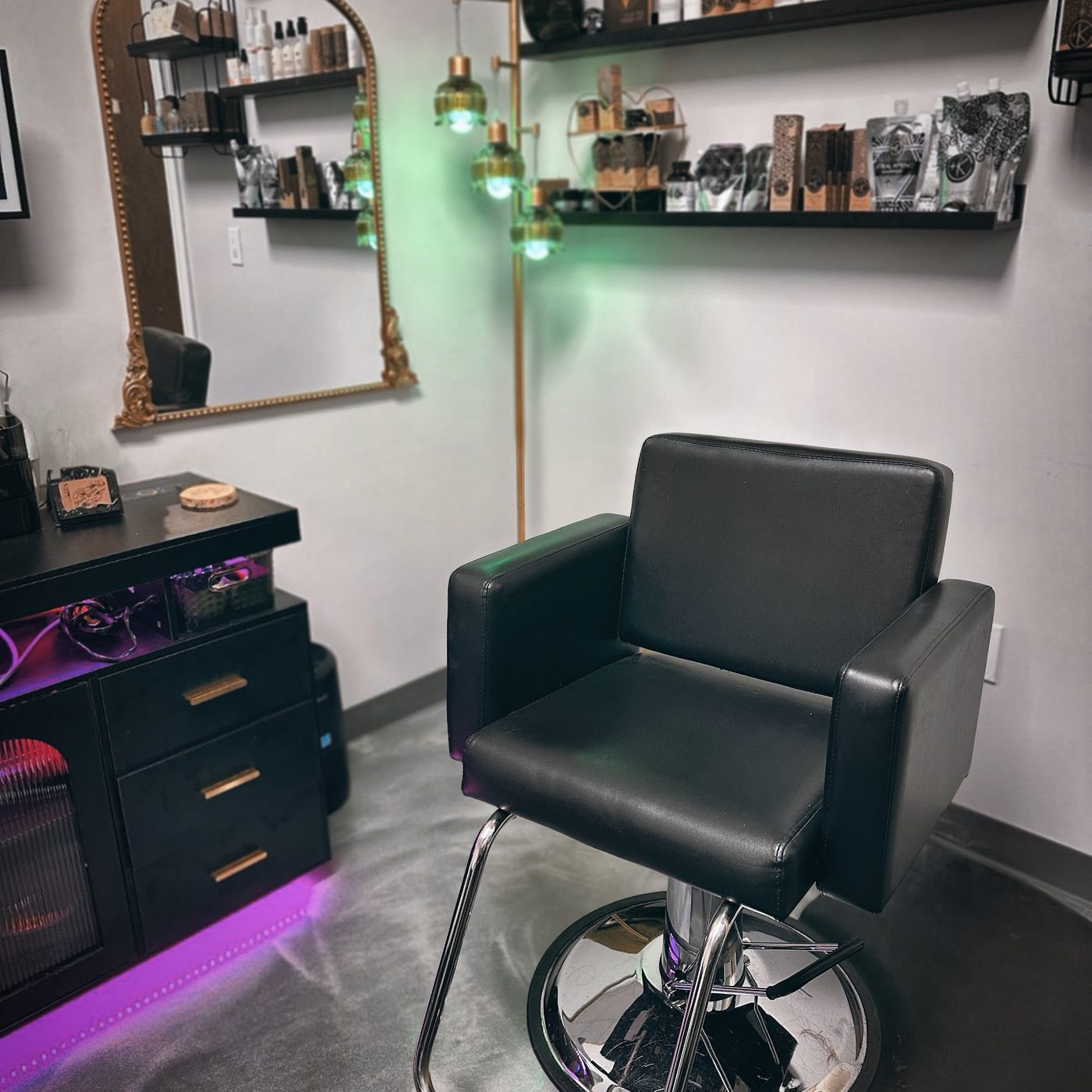 A styling station inside the suite with a gold-framed mirror, product shelves, and green glass lights